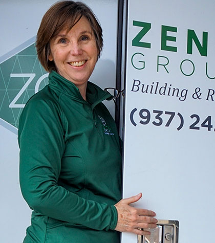 A person in a green jacket stands by a door with "ZEN Group Building & Remodeling" and a phone number on it.