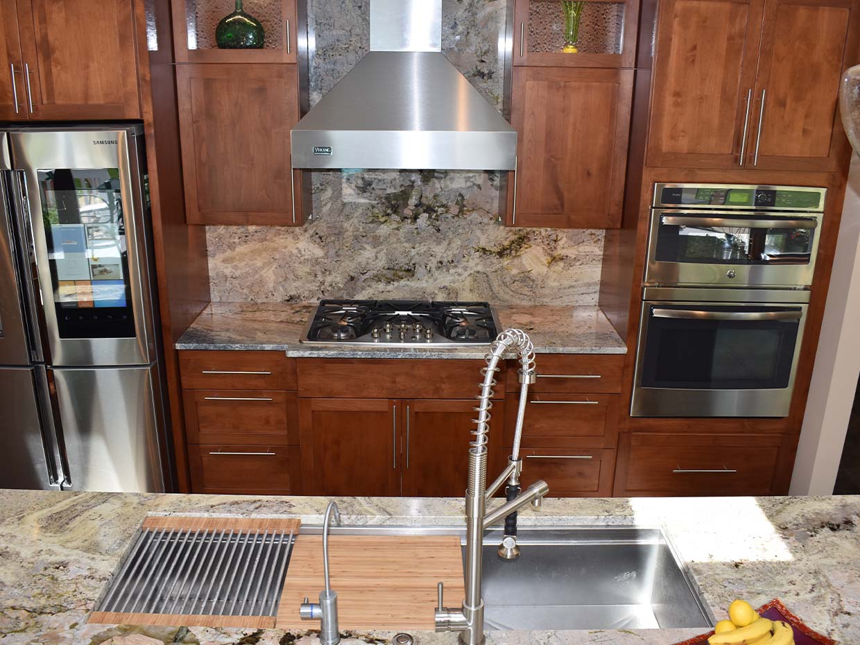 Modern kitchen with stainless steel appliances, granite countertops, a gas cooktop, and a chrome faucet with a sink.