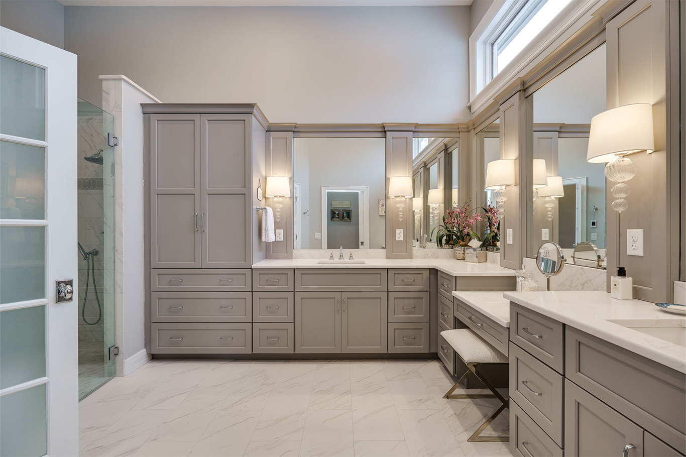 bathroom remdoel service page 3 Modern bathroom remodeling Dayton showcase with gray cabinets, double sinks, large mirrors, a vanity area with bench seating, marble floors, and a walk-in shower with glass door.