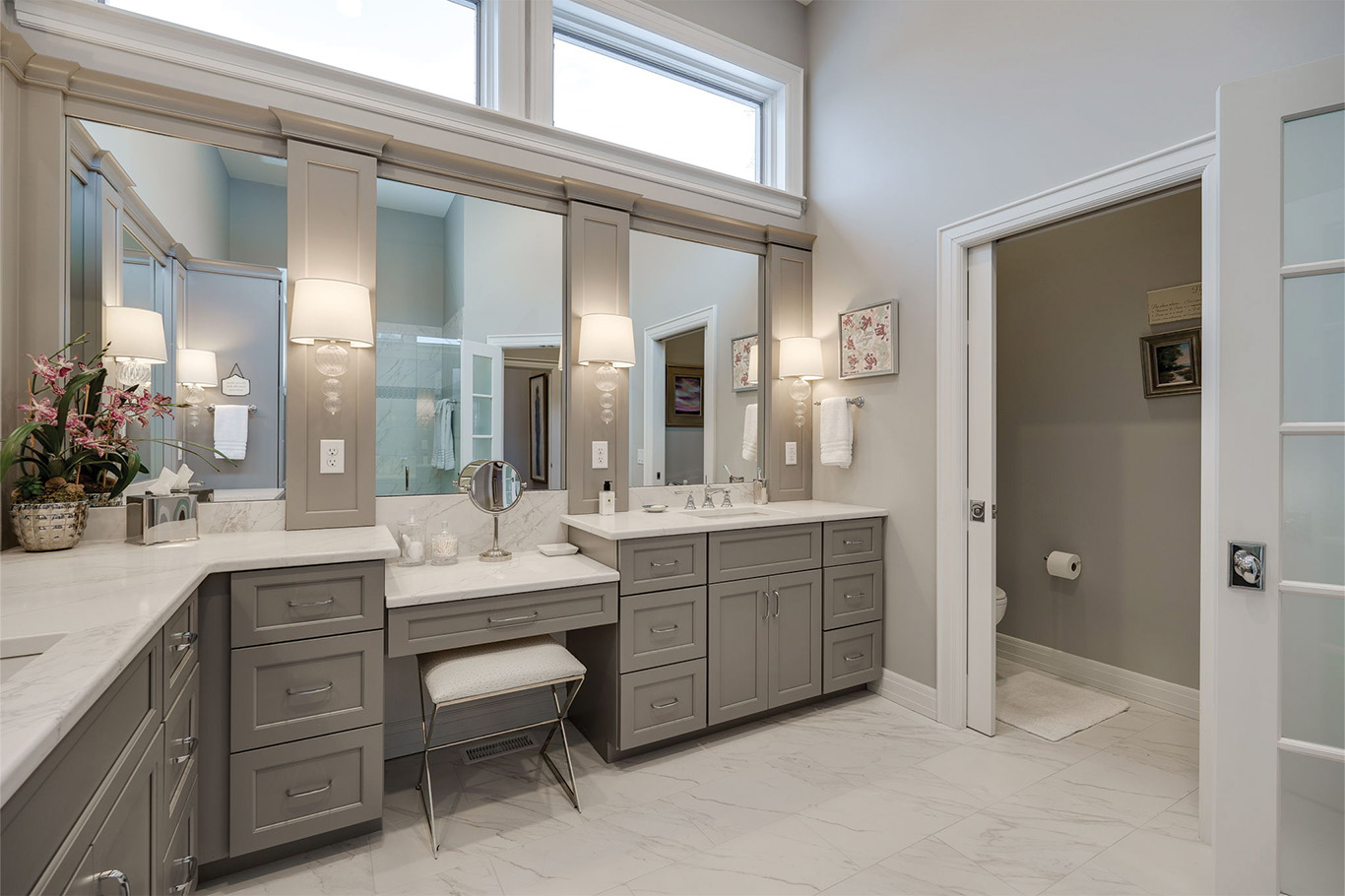 bathroom remodel service page 6 Modern bathroom with gray cabinets, white countertops, dual sinks, a vanity area with a bench, marble floor, and a separate room for the toilet—perfect inspiration for bathroom remodeling Dayton homeowners will love.