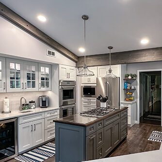 Modern kitchen with white cabinets, stainless steel appliances, a center island cooktop, pendant lights, wooden floors, and a handy pricing guide for your renovation needs.